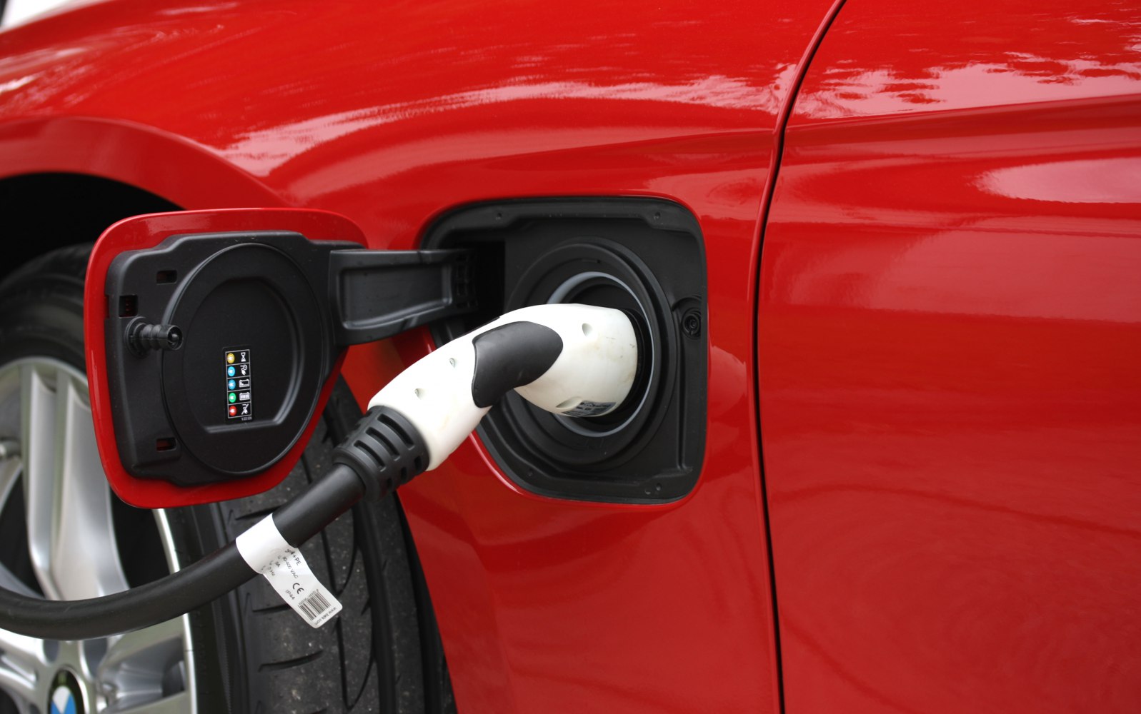 Electric charging port with plug inserted on red vehicle