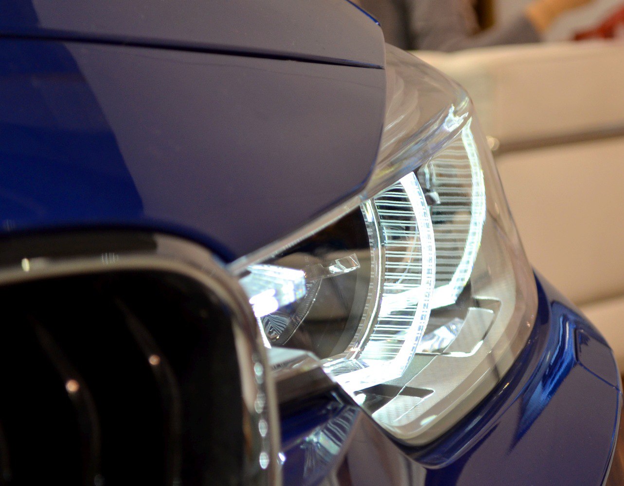 Close-up of LED headlight and front grille on blue vehicle front.