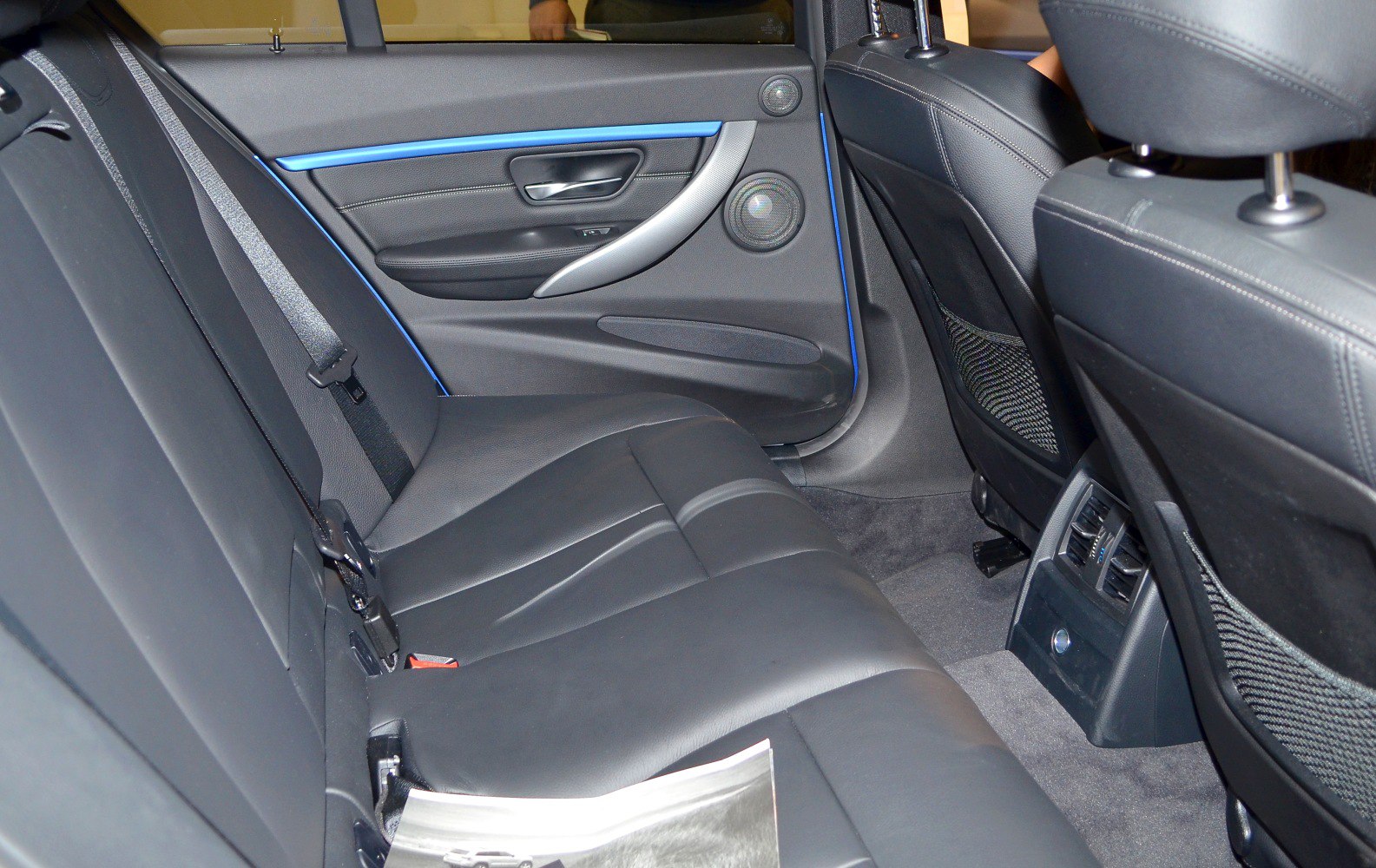 Black leather rear seats with blue trim, door speakers, and rear ventilation
