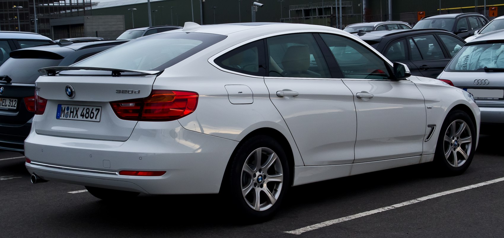 Rear side view of white hatchback with distinct BMW tail lights and alloy wheels.
