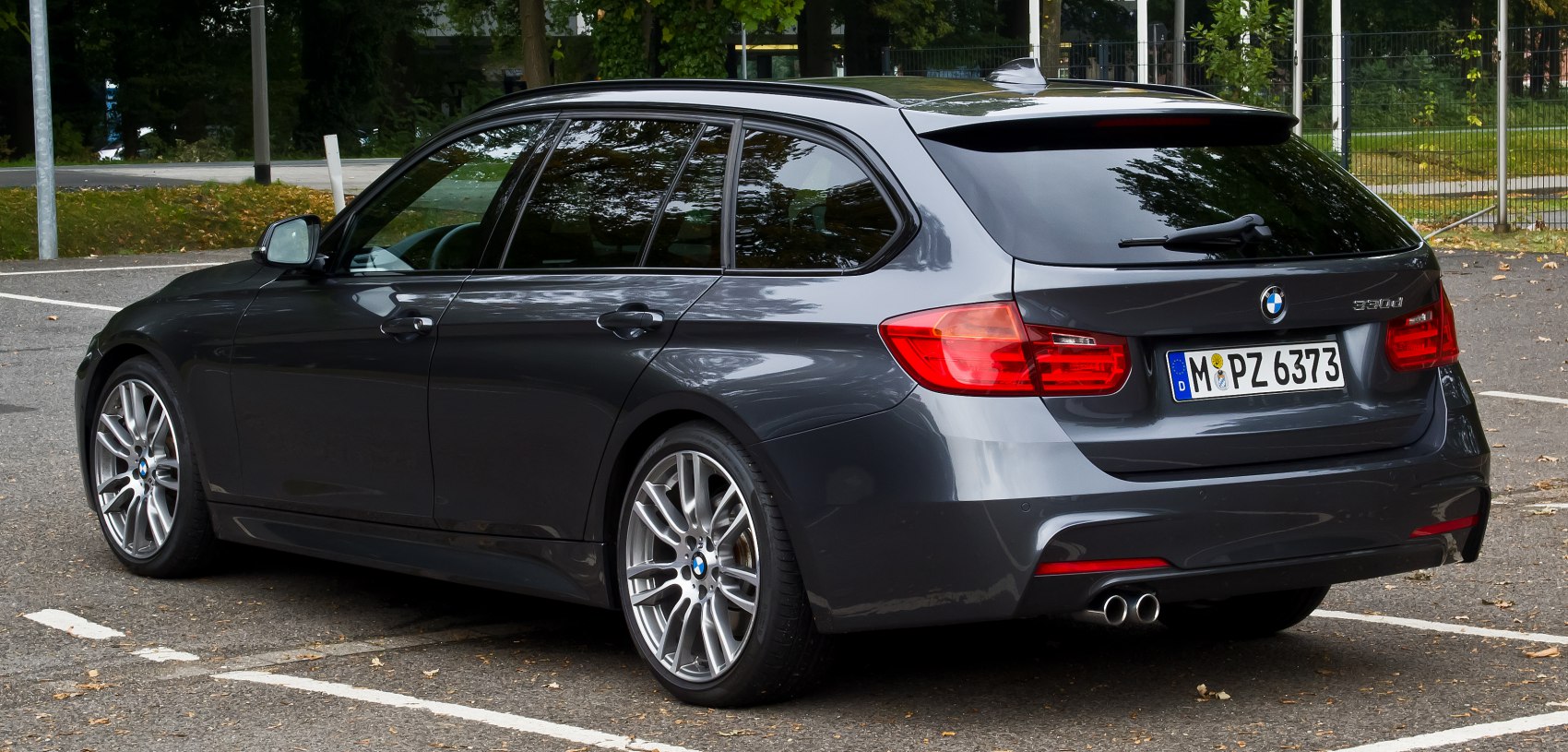 Rear and side view of a dark metallic station wagon with dual exhaust and alloy wheels