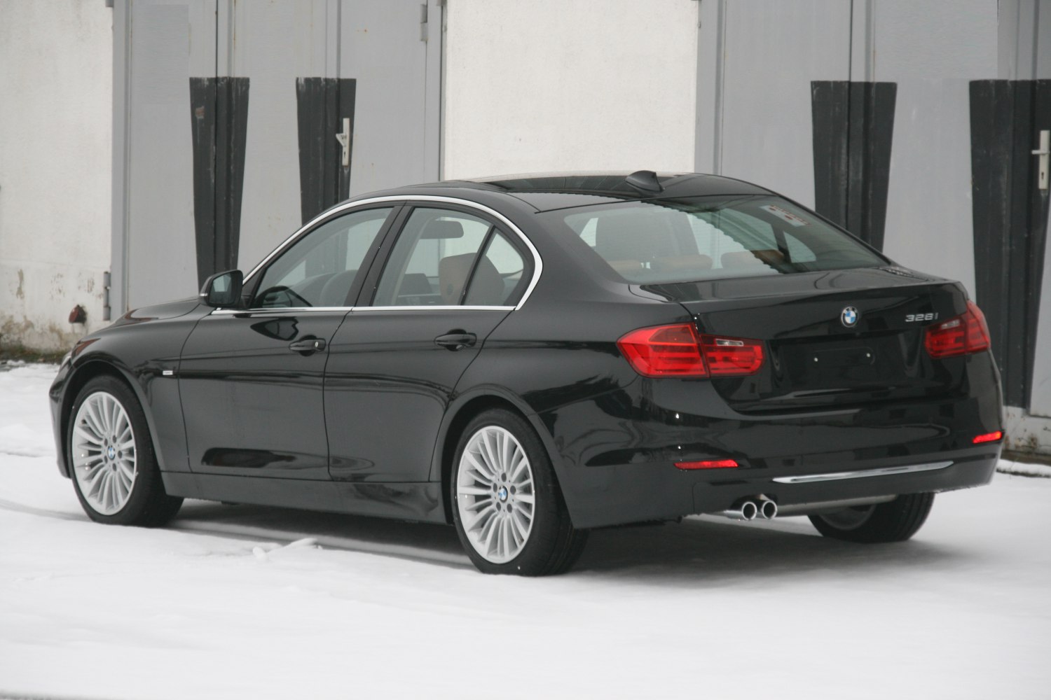 Black sedan with dual exhaust and alloy wheels on snow