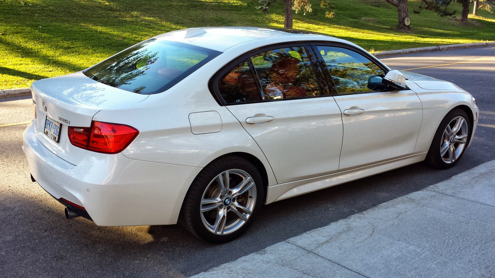 White sedan rear side view with alloy wheels and taillights
