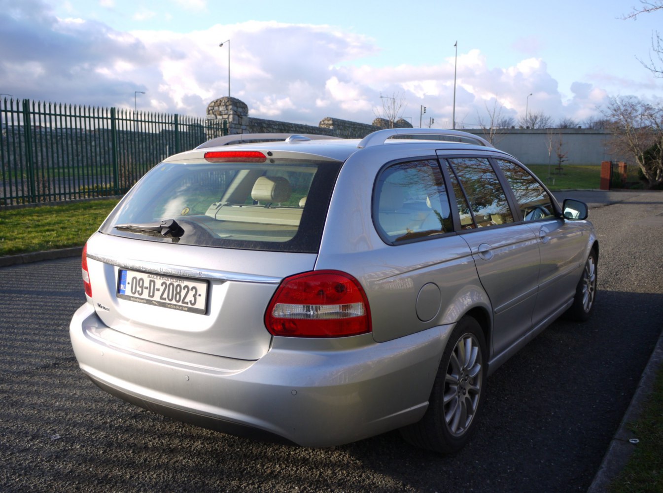 Rear and side view of silver estate car with roof rails and red taillights