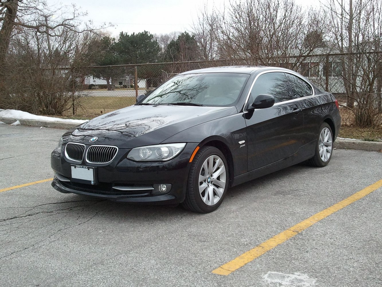 Black coupe with kidney grille and curved headlights parked in outdoor lot