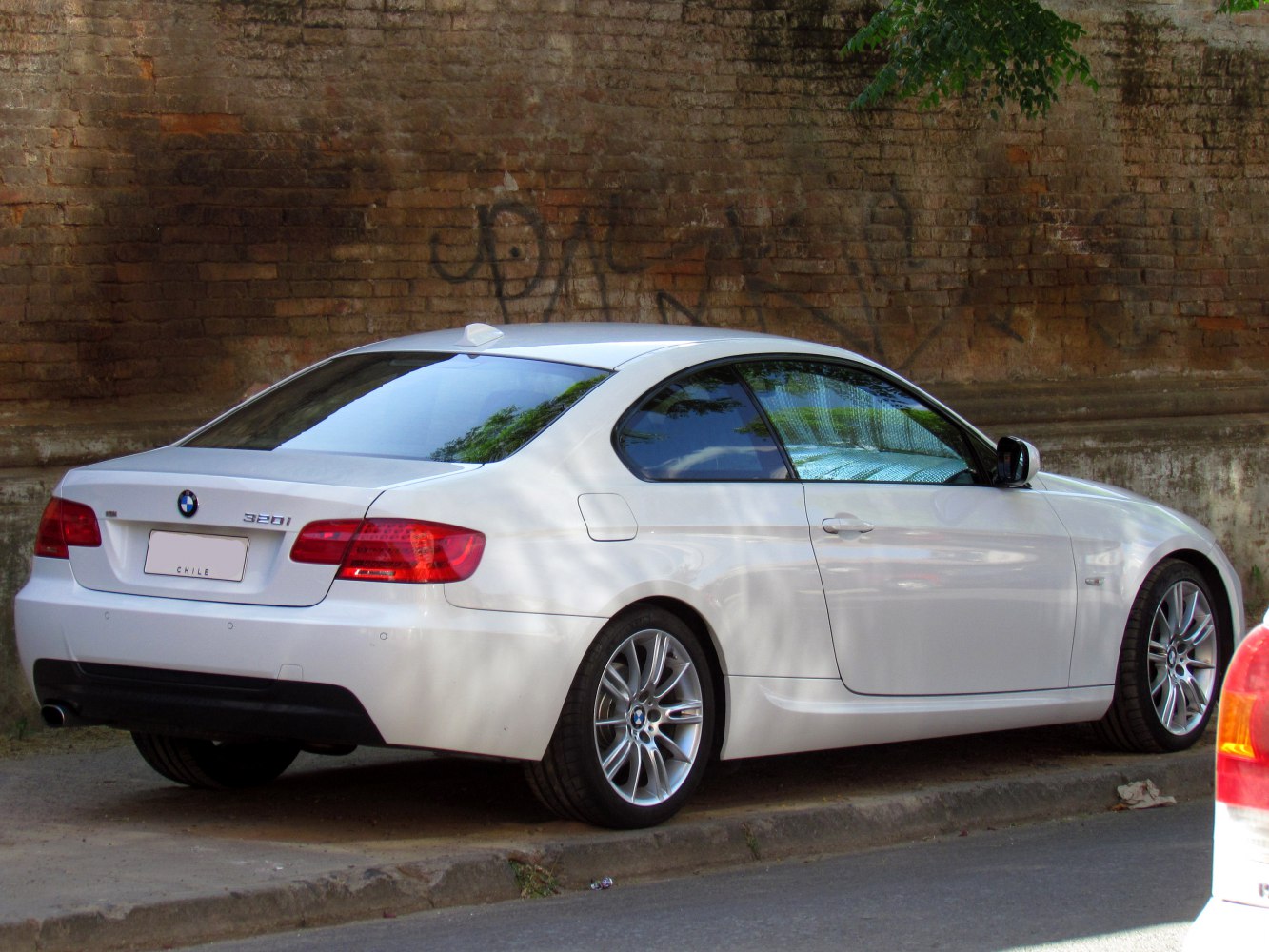 Rear side profile of a sleek white coupe with distinctive taillights and alloy wheels