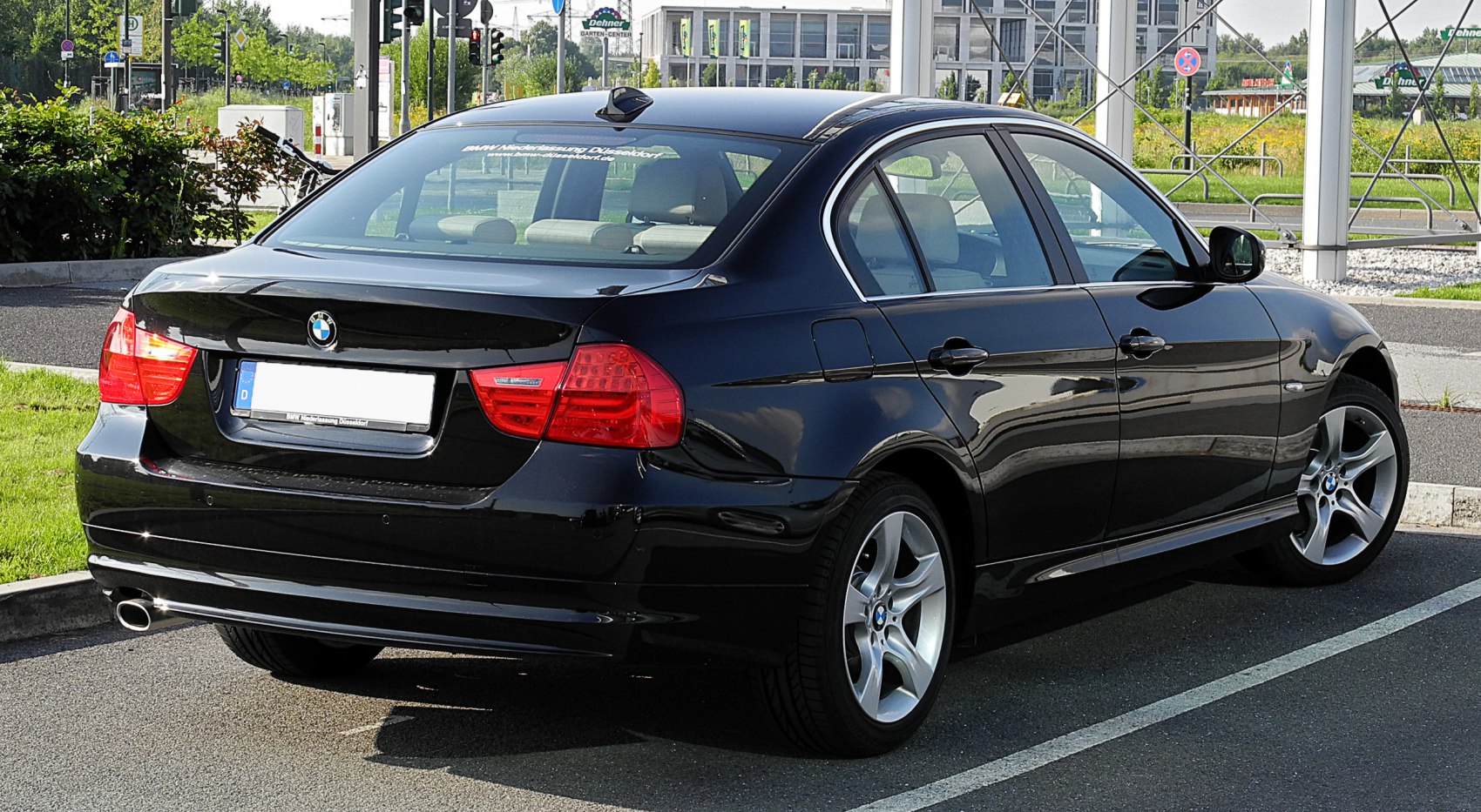 Rear and side view of a black sedan with alloy wheels and clear taillights