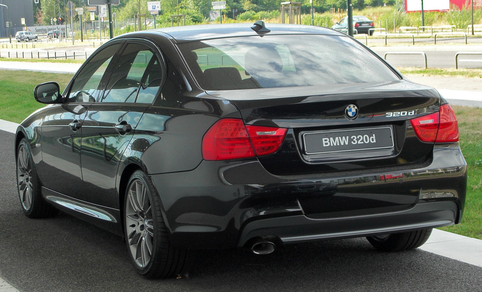 Rear and side view of black sedan with distinctive tail lights and exhaust.