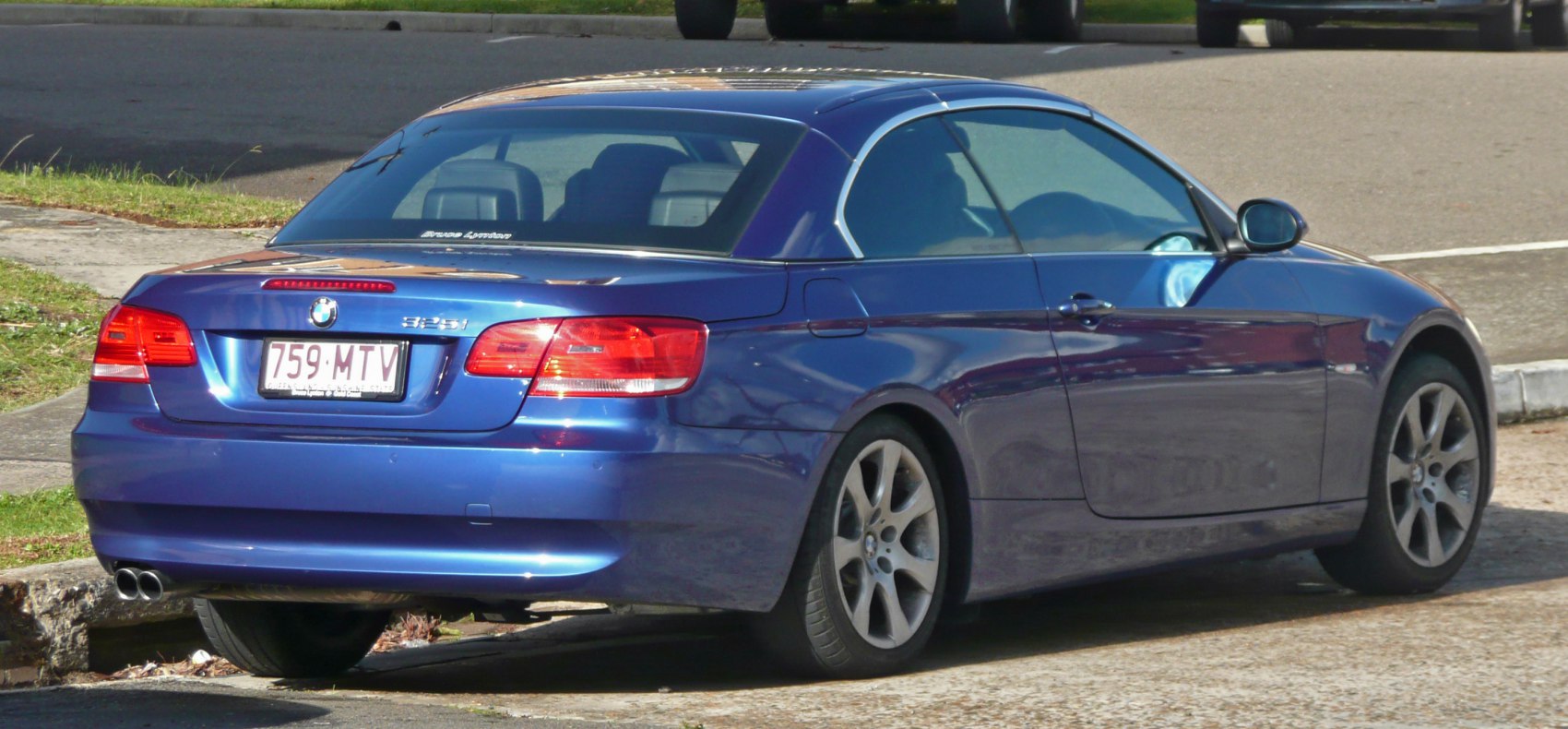 Rear view of blue hardtop convertible with dual exhaust and taillights.