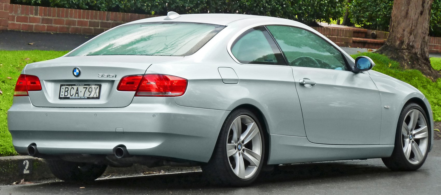 Silver coupe rear with taillights, dual exhaust, and alloy wheels