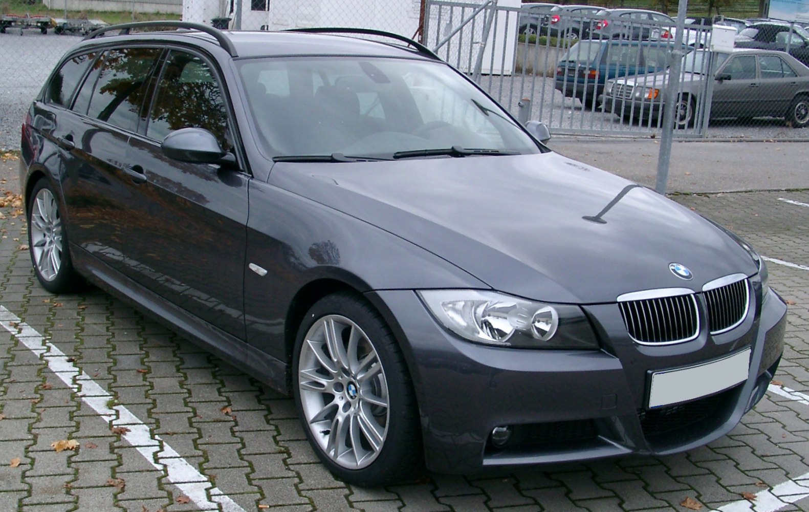 Front-angle view of dark grey 3 Series Touring with alloy wheels and roof rails