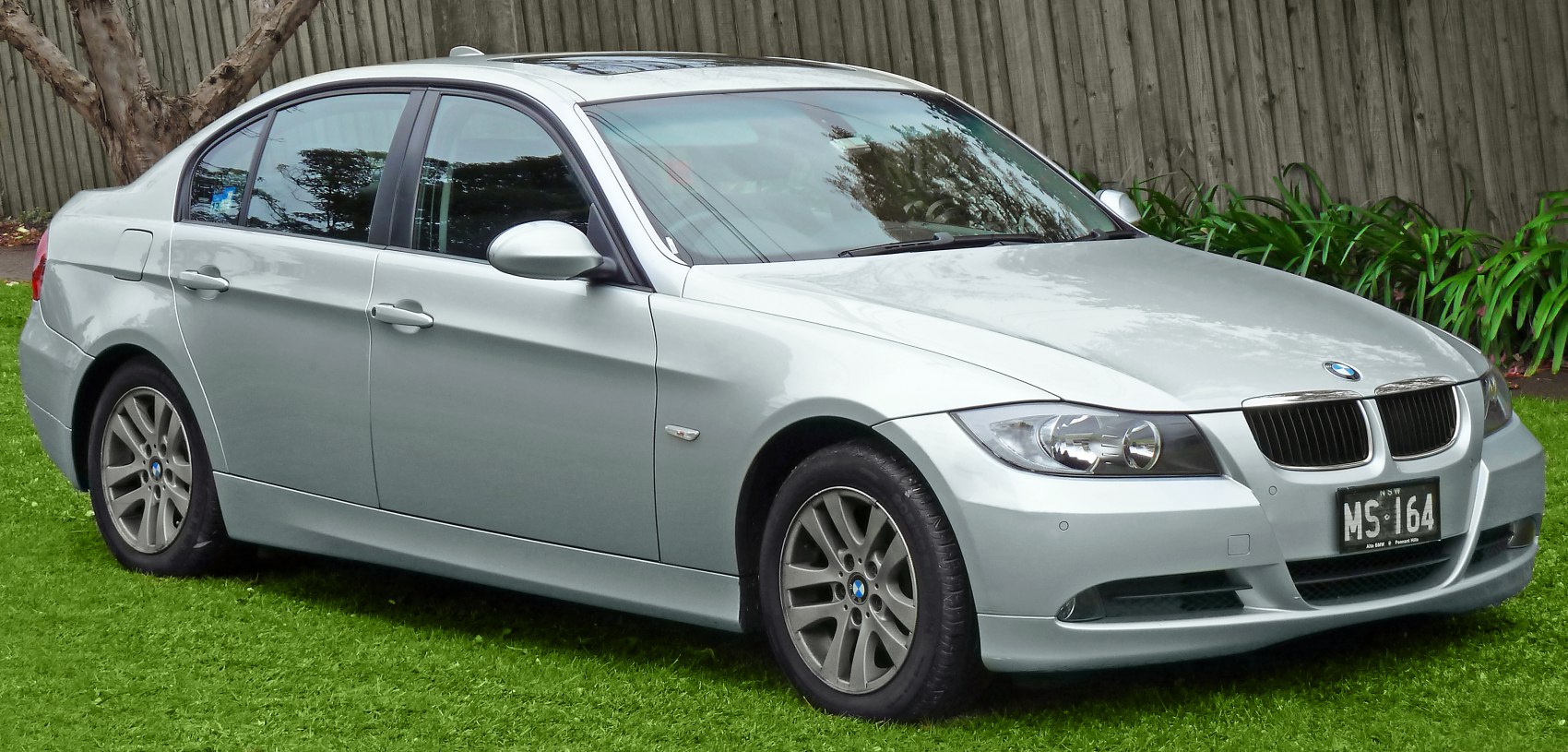Side front view of a silver sedan with classic headlights and alloy wheels
