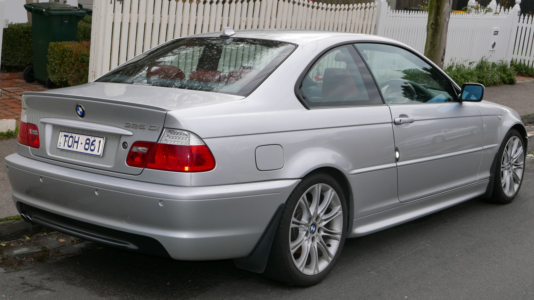 Silver two-door coupe rear-side view with alloy wheels and clear rear lamps.