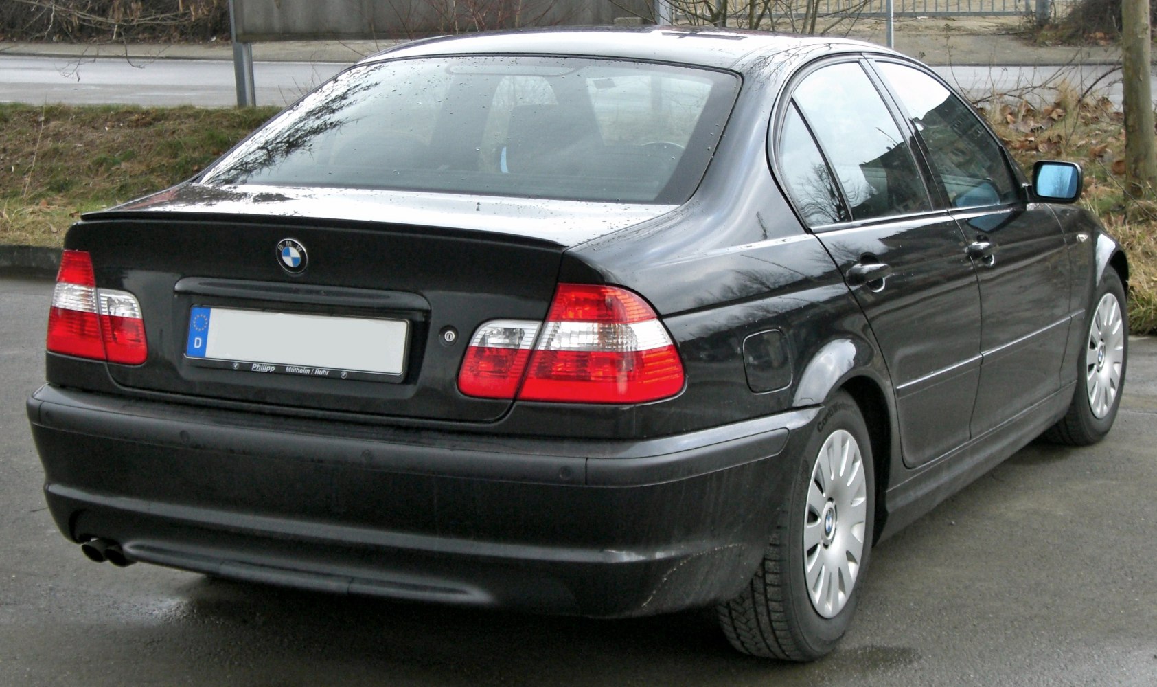 Rear perspective of black sedan with dual exhaust and clear segmented tail lights