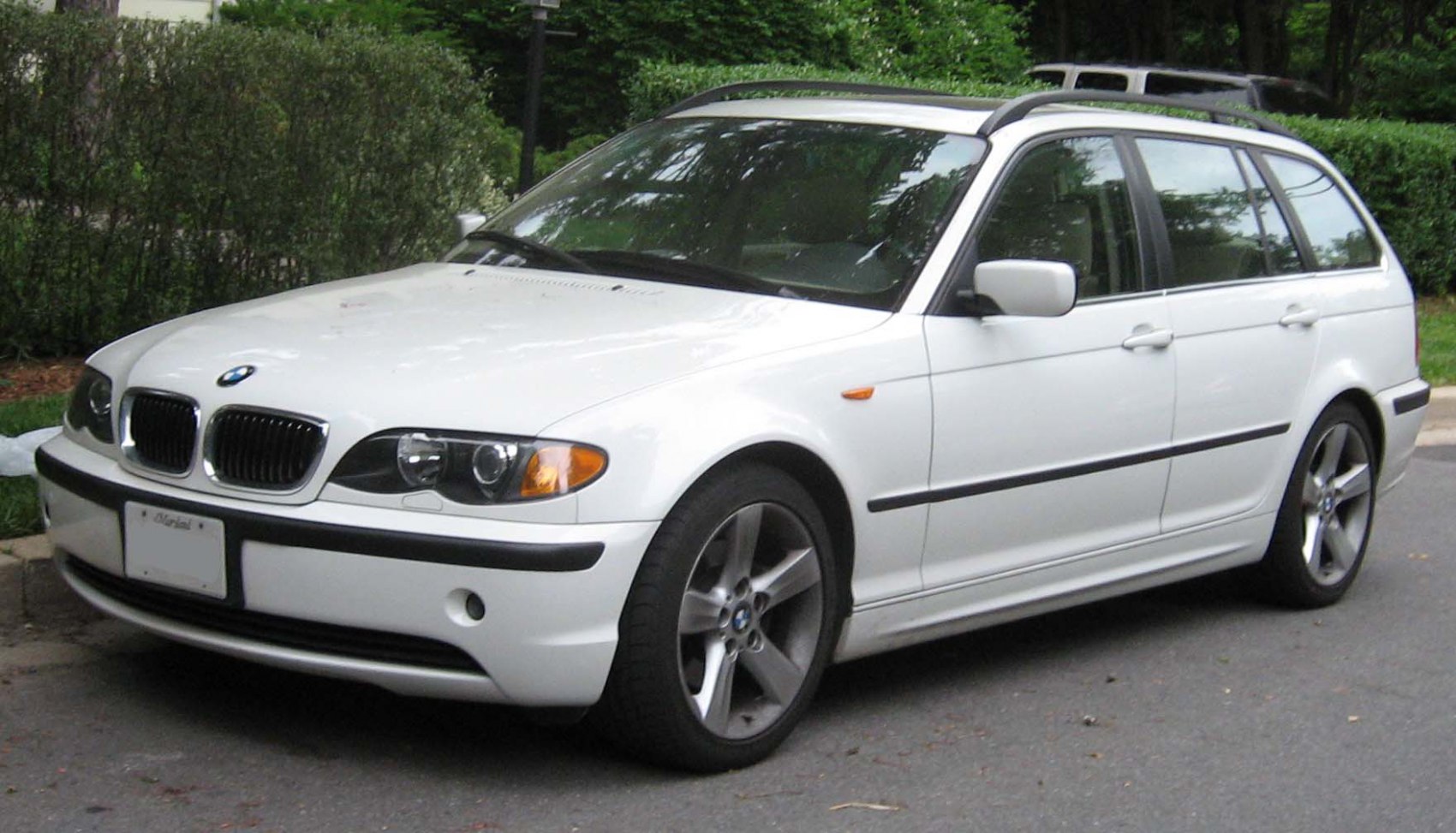 White BMW 3 Series Touring front and side view with alloy wheels and roof rails