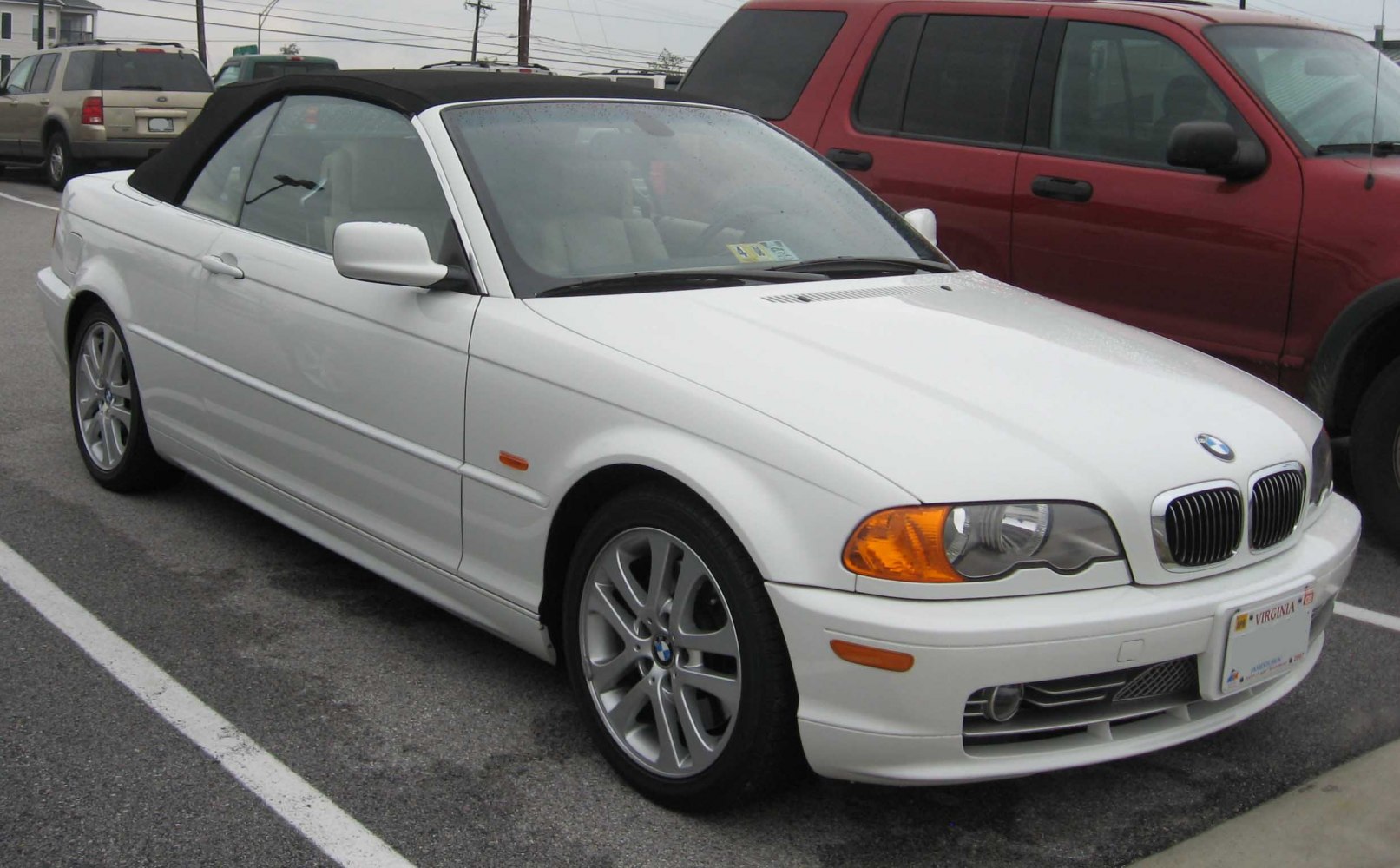White convertible with black soft top and alloy wheels front side view