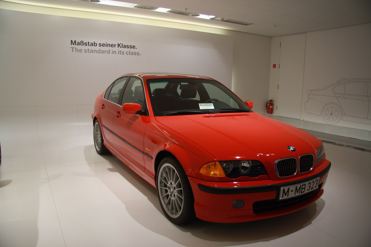 Red sedan with sporty multi-spoke wheels, front-side view highlighting classic design and BMW grille