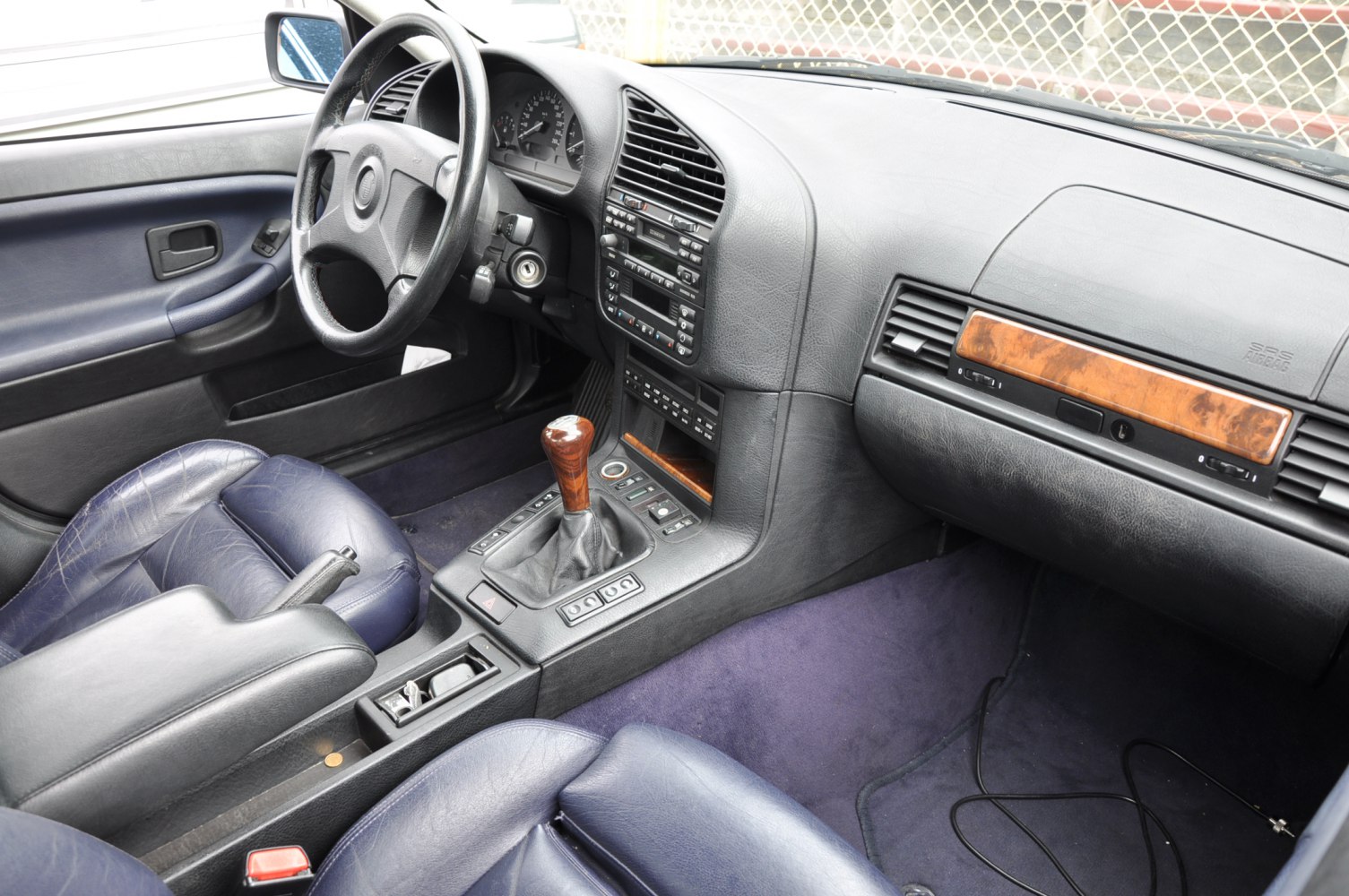 Wooden gear lever knob and wood trim dashboard with blue leather seats.