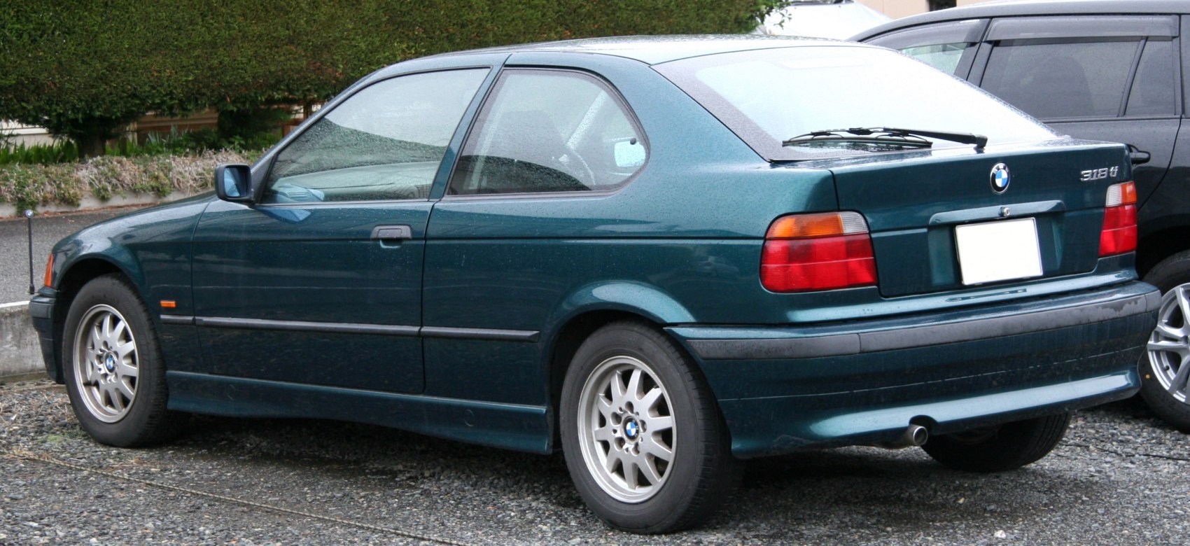 Rear side view of a sporty two-door hatchback with alloy wheels and classic design.