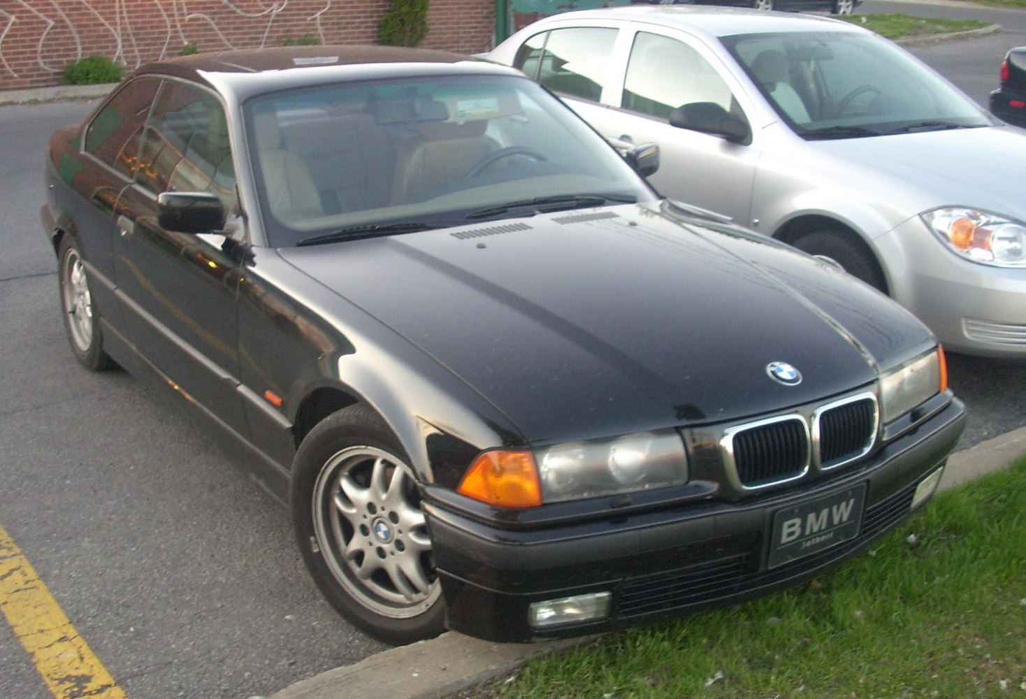 Front and side view of black coupe with twin kidney grille and alloy wheels