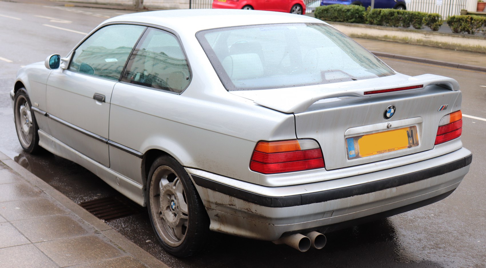 Rear view of a coupe with spoiler and dual exhaust pipes