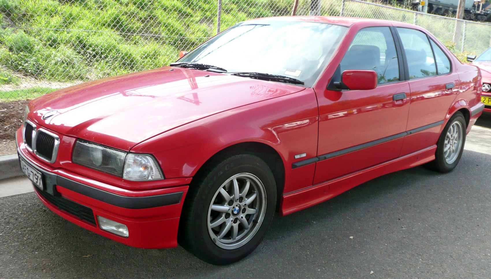 Red classic sedan with alloy wheels and front-side view