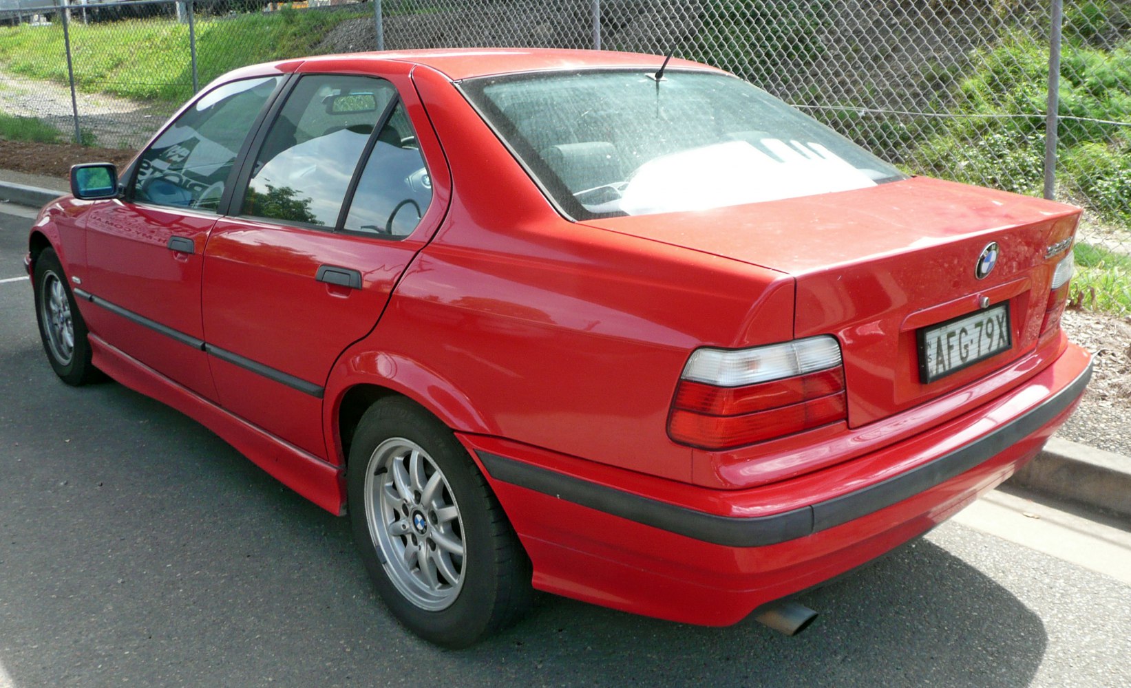 Red sedan rear side with alloy wheels and taillights