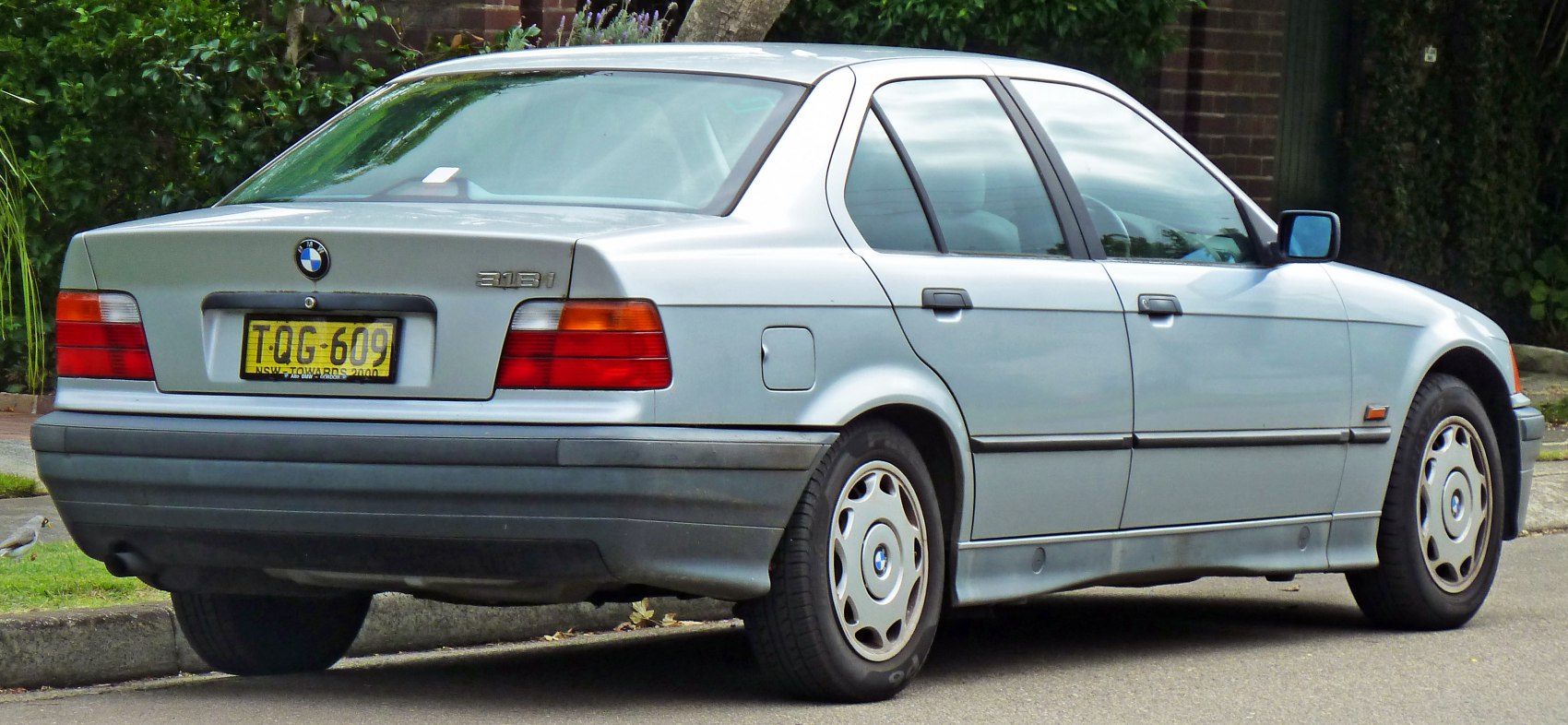 Rear side view of a classic 1991 sedan with distinct taillights and alloy wheels
