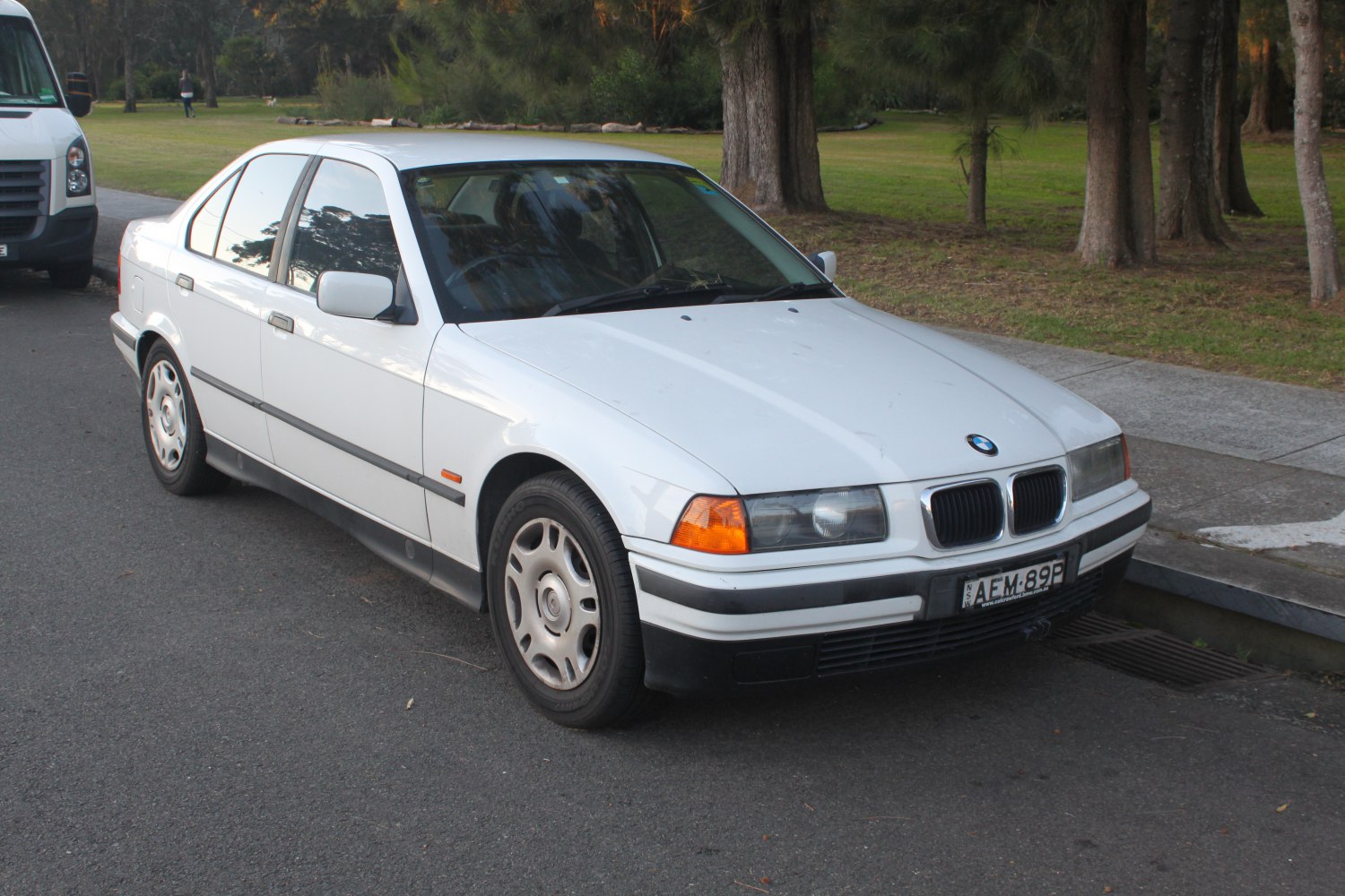 Front-side view of white sedan with rectangular headlights and distinct grille.