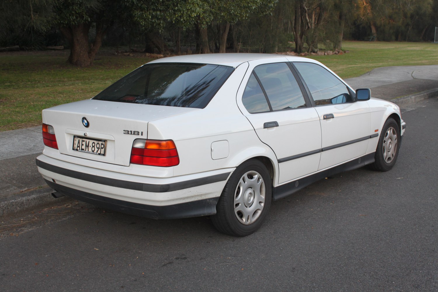Rear-side view of white 1990s sedan with classic tail lights