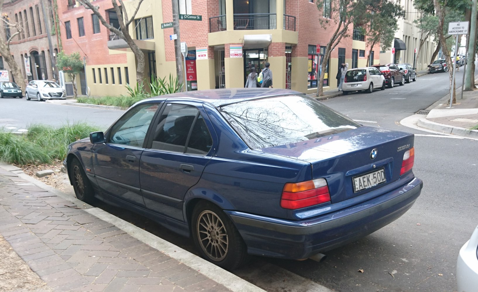 Rear side view of a 1990s sedan with distinct tail lights and alloy wheels