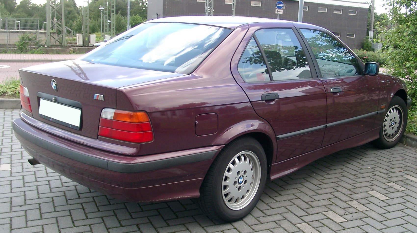 Rear and side view of a classic BMW 3 Series sedan with alloy wheels and vintage design.