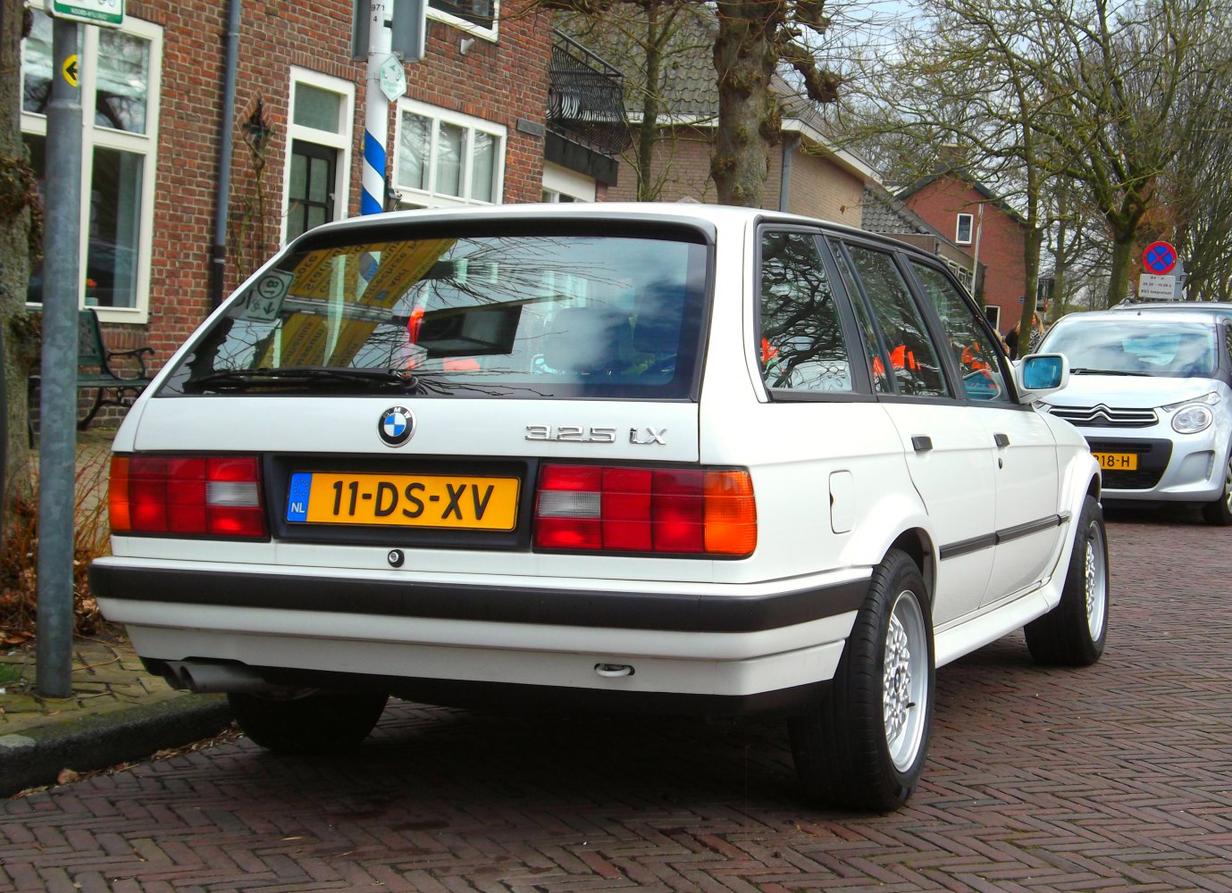 Rear view of a classic white station wagon with distinct tail lights and black bumper trim