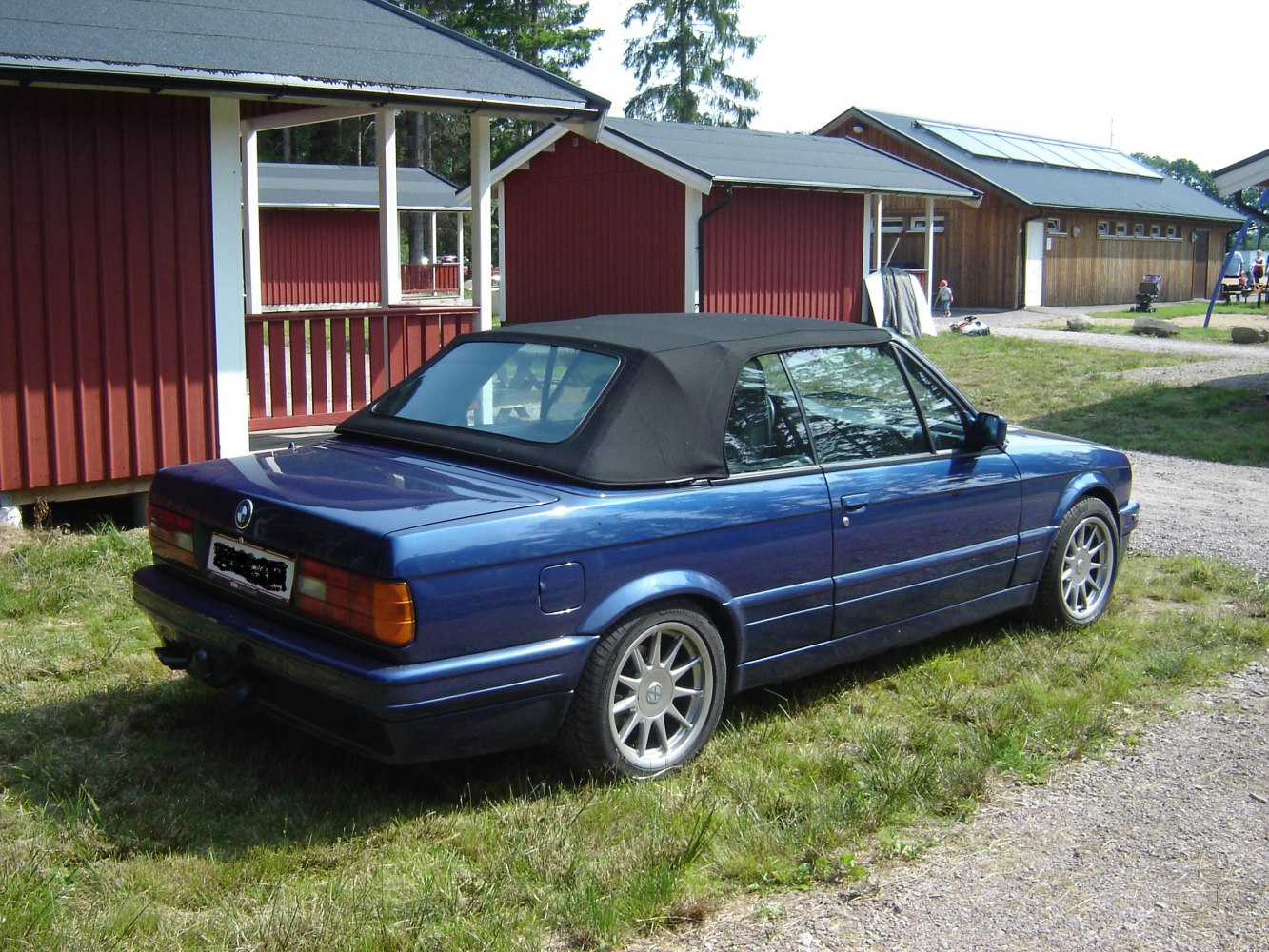 Rear-side view of classic convertible with closed soft top and alloy wheels