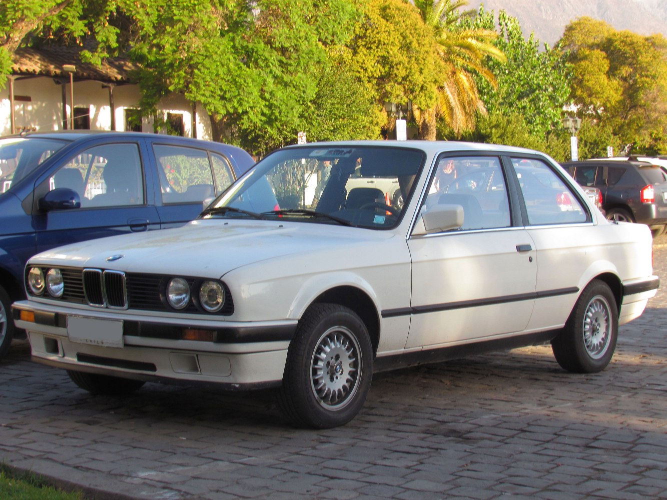 Front and side profile of classic two-door coupe with quad headlights and alloy wheels.