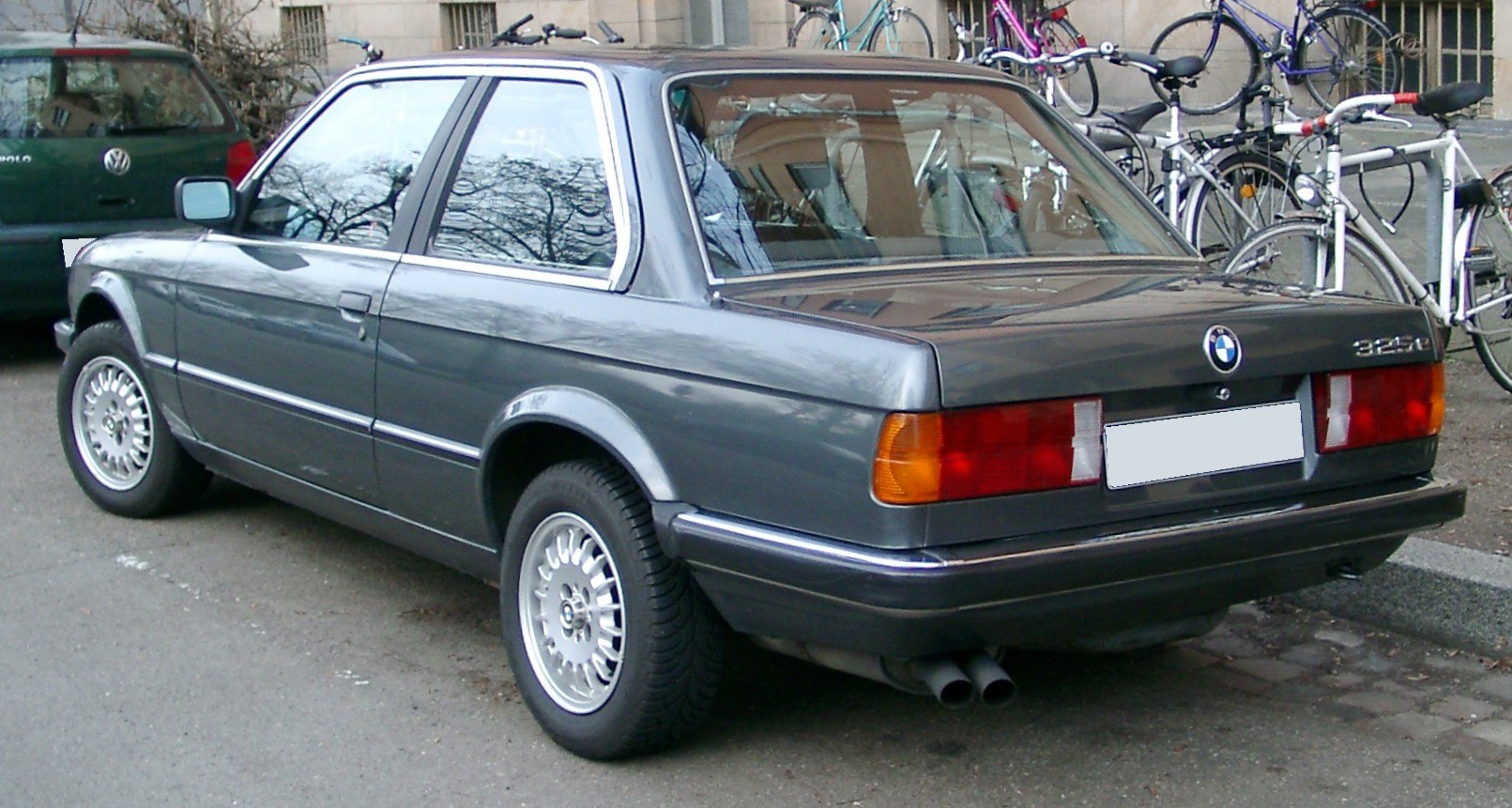 Rear quarter view showing taillights, wheels, and dual exhaust of vintage coupe.