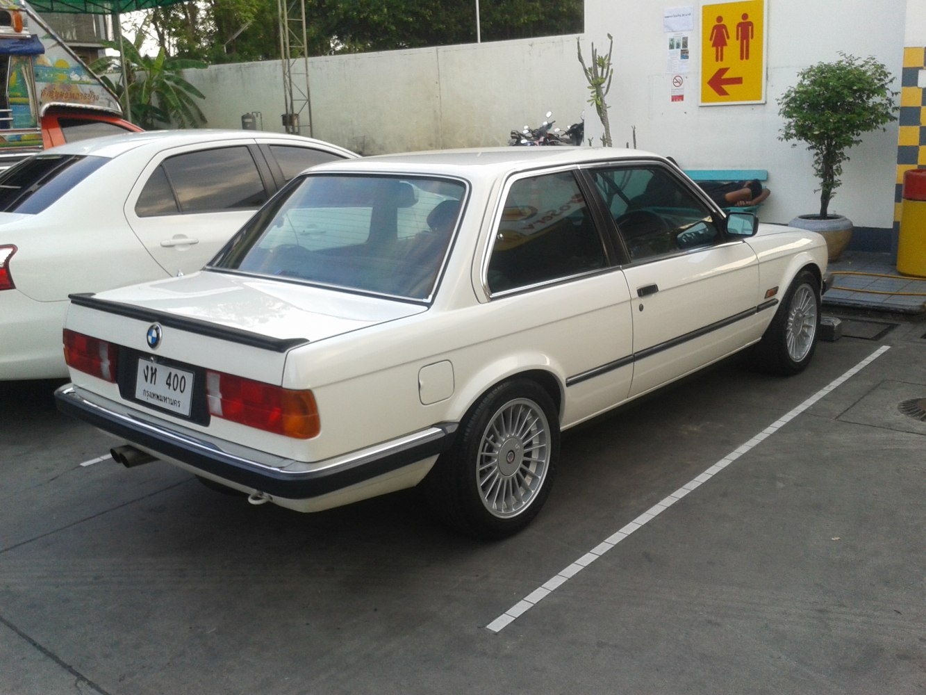 Rear-side view of classic coupe with spoiler and multi-spoke wheels.