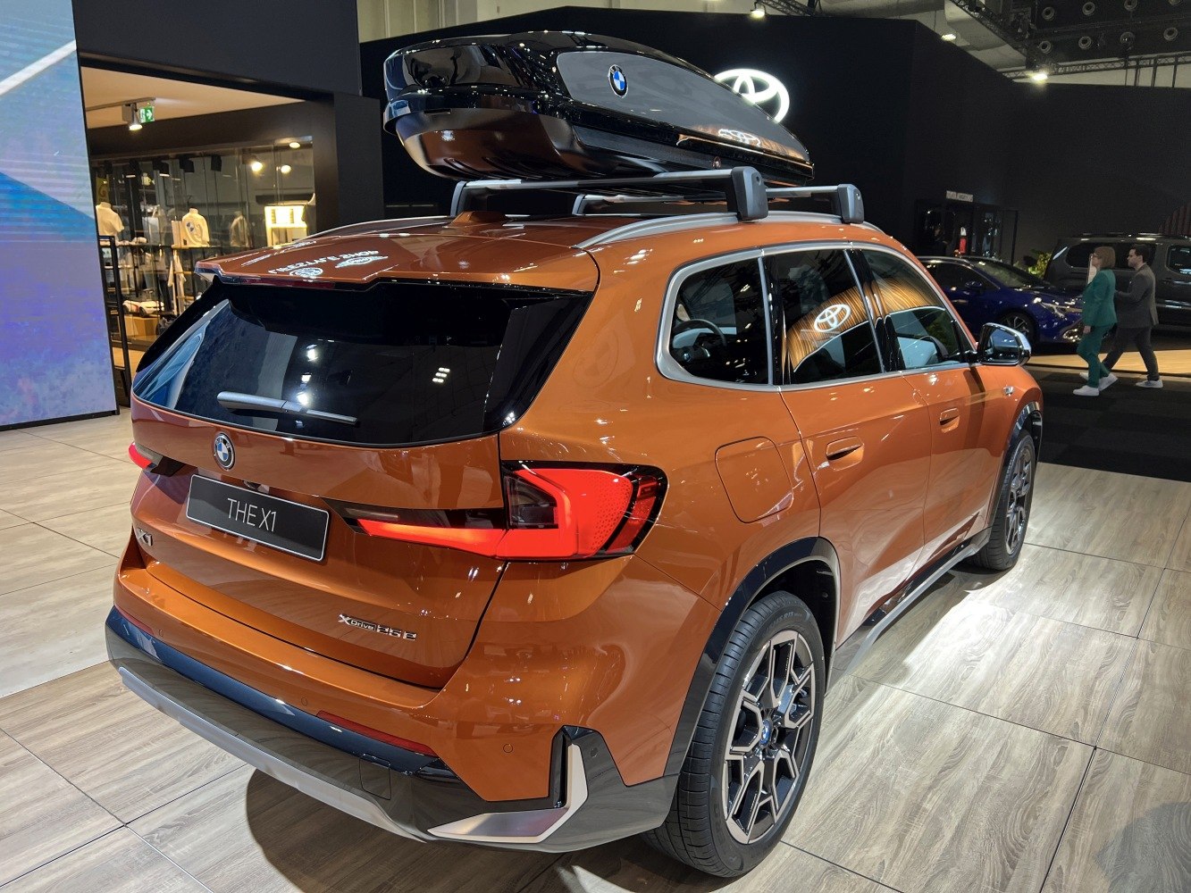 Rear view of metallic brown SUV with roof box and modern taillights