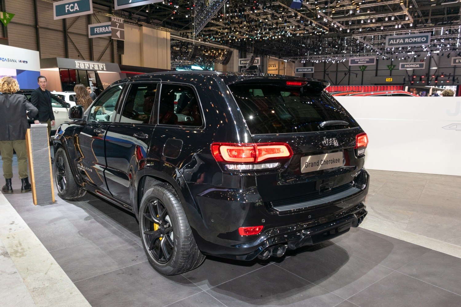 Black SUV rear side with quad exhaust pipes and glossy finish