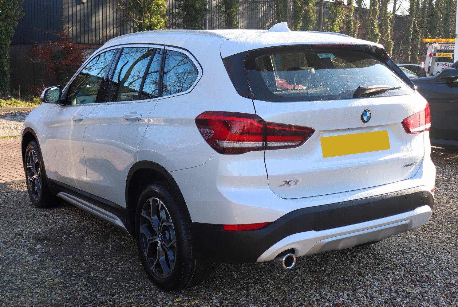 Rear and side view of white SUV with distinctive taillights and single exhaust