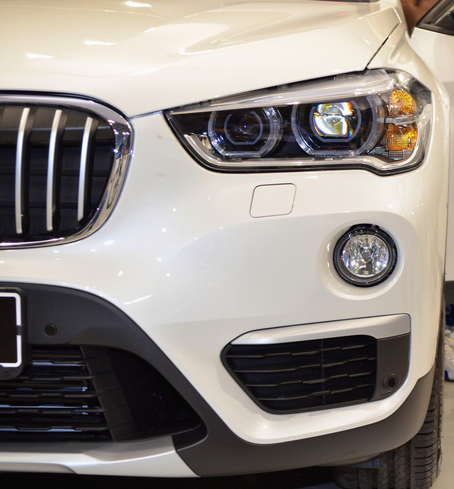 Front headlight, grille, and fog light detail of white SUV