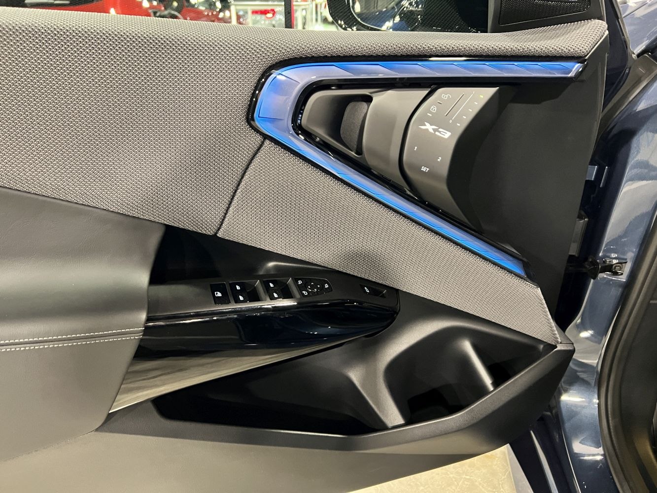Interior door panel with ambient blue lighting and control buttons