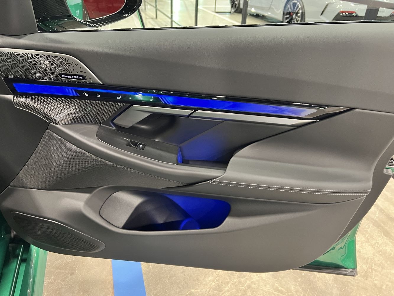 Interior door panel with ambient blue lighting and premium speaker.