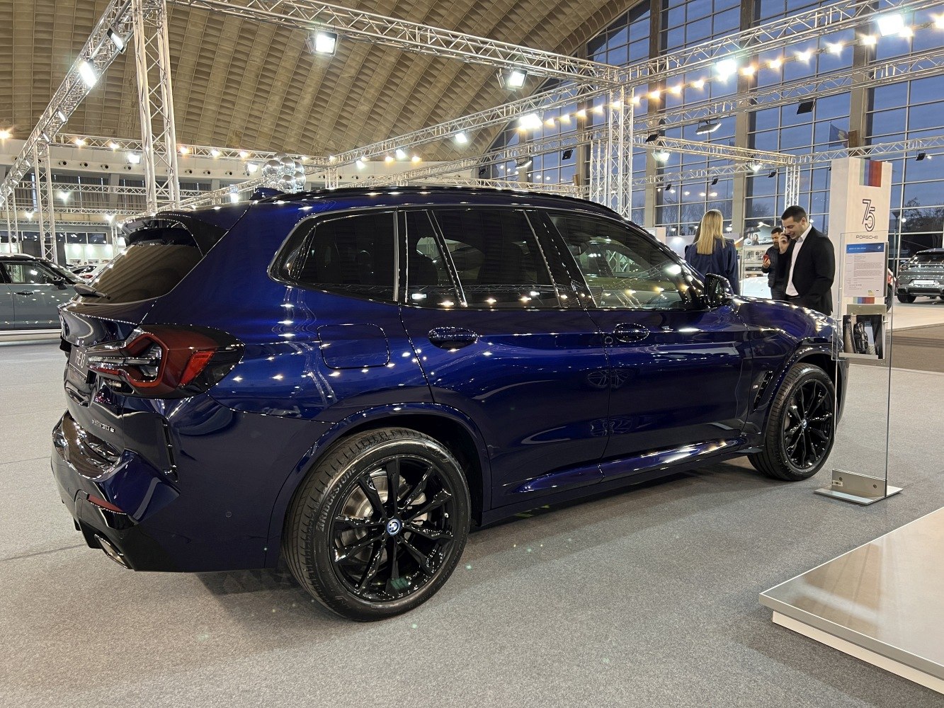 Side and rear view of dark blue SUV with black wheels in showroom