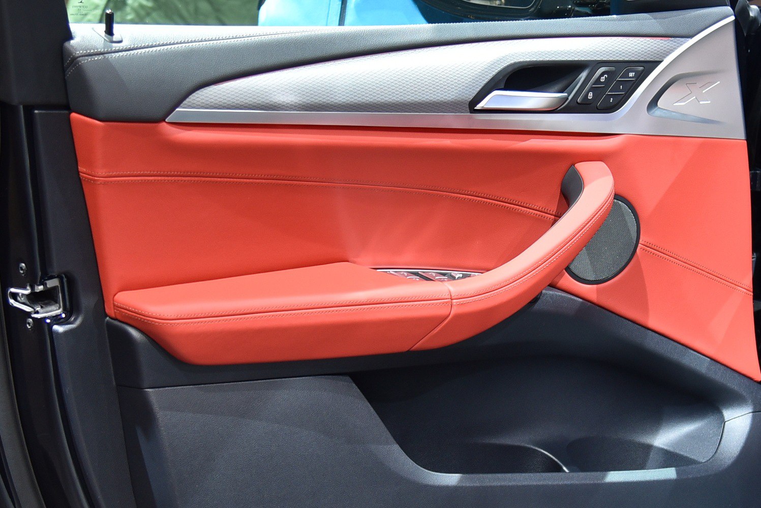 Red leather interior door panel with built-in controls and speaker