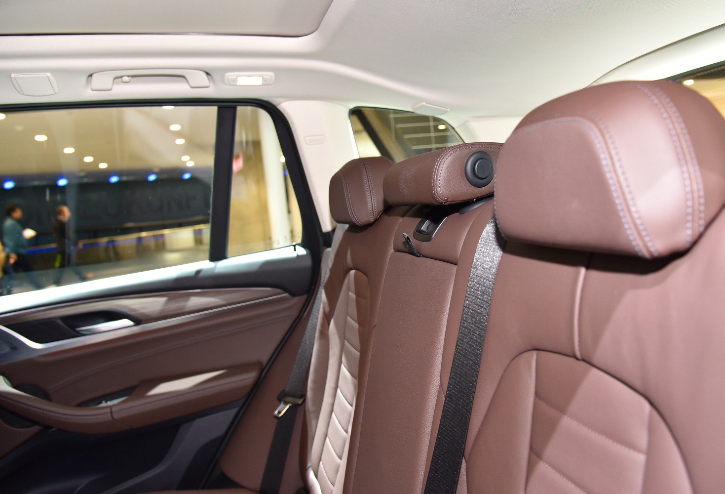 Close-up of brown leather rear seats with headrests and seatbelt.