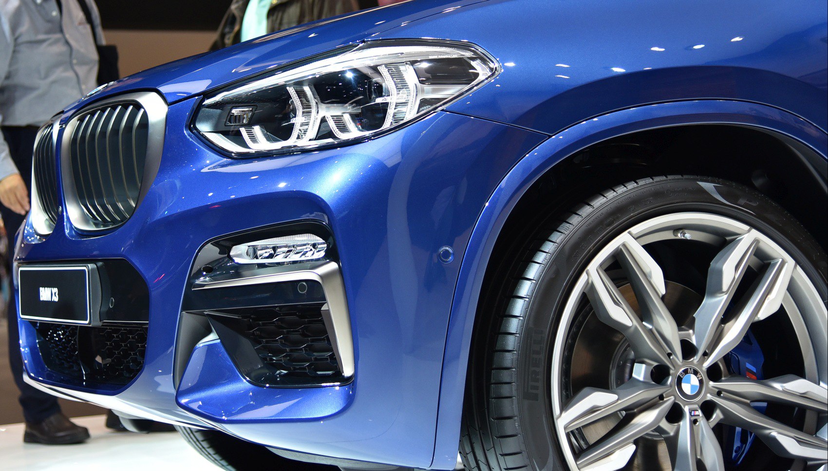 Close-up of front grille, headlight, and alloy wheel in blue finish