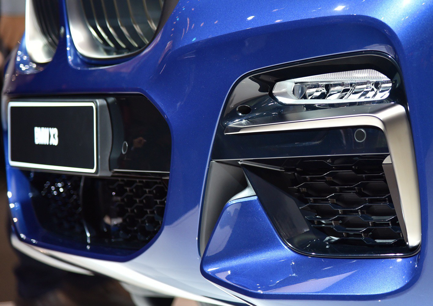 Close-up of front grille and LED headlight with blue paint