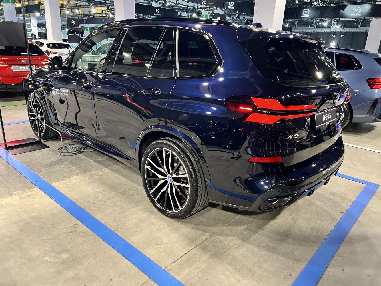 Rear and side view of SUV with black multi-spoke wheels and charging port
