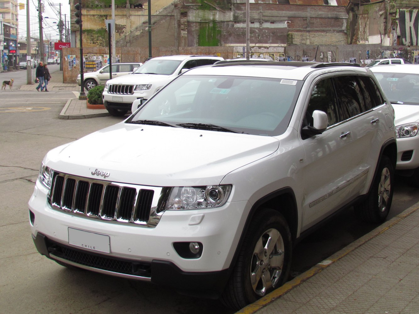 Front grille and headlights of a white SUV parked on city street